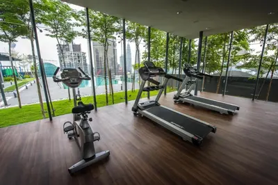 a gym with three exercise bikes in a room with windows at Maxhome@Dorsett Residence , KL in Kuala Lumpur