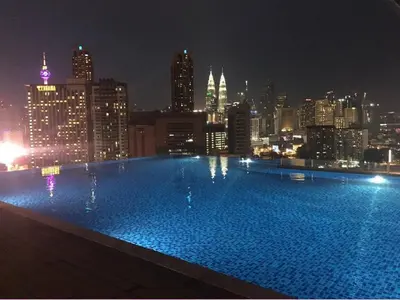 a large swimming pool with a city skyline at night at Maxhome @ D'Majestic Place, KL City Centre in Kuala Lumpur