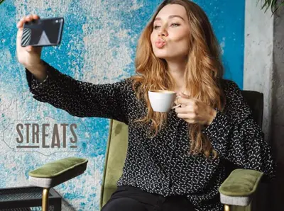 a woman sitting in a chair holding a cup of coffee at Ibis Styles Kuala Lumpur Fraser Business Park in Kuala Lumpur