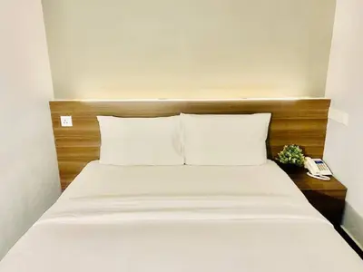 a bed with white sheets and a wooden head board at Asia Like Boutique Hotel in Kuala Lumpur