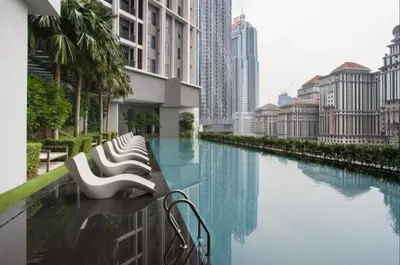 a row of white benches next to a river in a city at KLCC The Mews Home in Kuala Lumpur