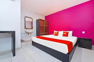 a bedroom with a large bed with a pink wall at Hotel O Elwarda Klcity in Kuala Lumpur