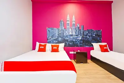 two beds in a room with a pink wall at Hotel O Elwarda Klcity in Kuala Lumpur