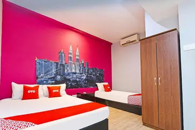 a room with two beds and a pink wall at Hotel O Elwarda Klcity in Kuala Lumpur
