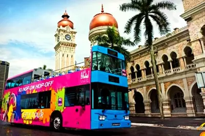 a double decker bus parked in front of a clock tower at AnCasa Hotel Kuala Lumpur, Chinatown in Kuala Lumpur