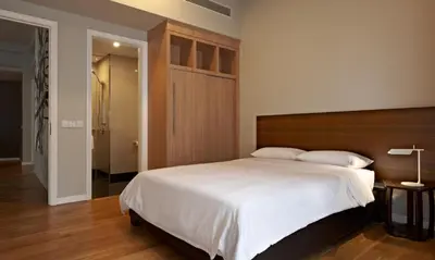 a bedroom with a large bed with a wooden headboard at E&O Residences Kuala Lumpur in Kuala Lumpur
