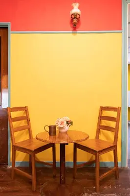 a table with two chairs and a yellow wall at Travel Hub Guesthouse in Kuala Lumpur