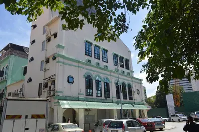 a white building with cars parked in front of it at Travel Hub Guesthouse in Kuala Lumpur