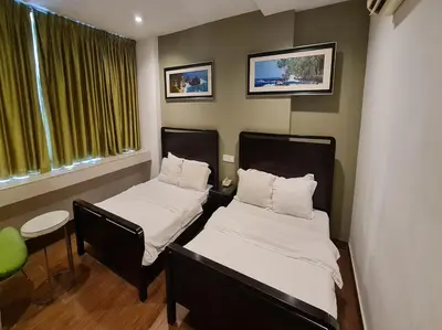 a small room with two beds and a chair at Hotel O Crossroads Hotel in Kuala Lumpur