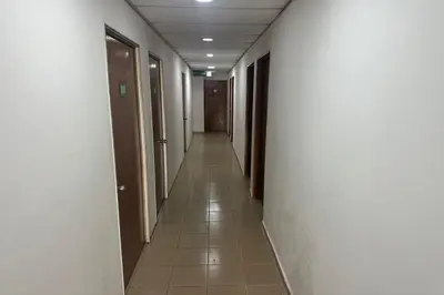 a hallway with white walls and a long hallway with brown doors at Sha La La Hostel in Kuala Lumpur