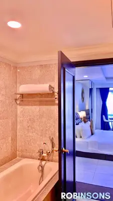 a bathroom with a tub and a bedroom with a bed at The Apartments at Times Square KL by Robinsons in Kuala Lumpur