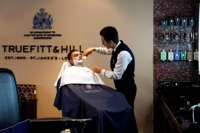 a man cutting a mans hair in a barber shop at The Majestic Hotel Kuala Lumpur, Autograph Collection in Kuala Lumpur