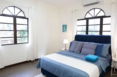 a bedroom with a blue bed with two windows at Omar's Place 1 in Kuala Lumpur