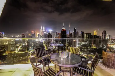 a table and chairs on a balcony with a city skyline at Regalia Residence The Sky Pool Suite in Kuala Lumpur