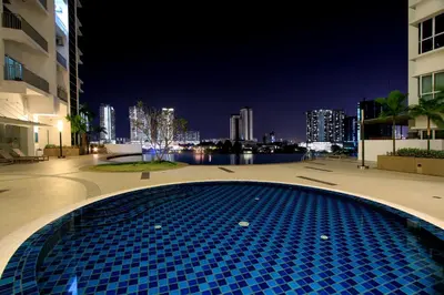a blue tile swimming pool in a city at night at Zeta Desky in Kuala Lumpur