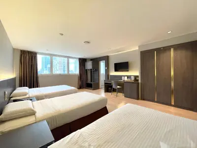 a hotel room with three beds and a desk at Hotel Imperial in Kuala Lumpur