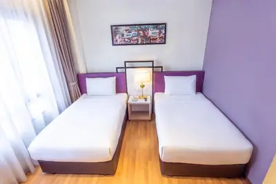 two twin beds in a room with a window at MPalace Hotel KL in Kuala Lumpur