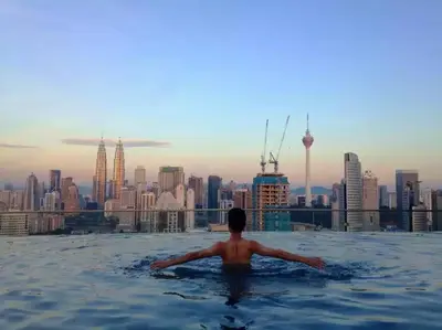 a man in a infinity pool with a view of a city at Maxhome@Regalia suite residence. KL in Kuala Lumpur