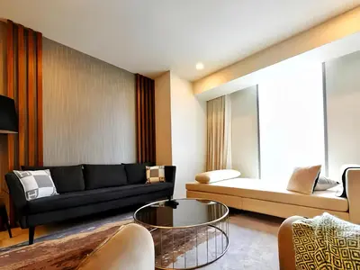 a living room with a black couch and a glass table at Tropicana The Residence KLCC in Kuala Lumpur
