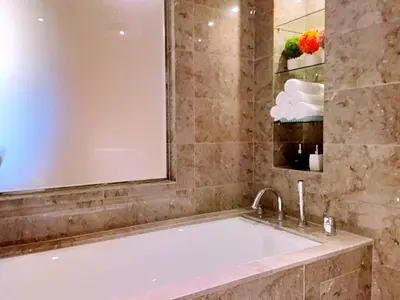 a bath tub in a bathroom with a mirror at Dorsett Residences Sri Hartamas KL in Kuala Lumpur