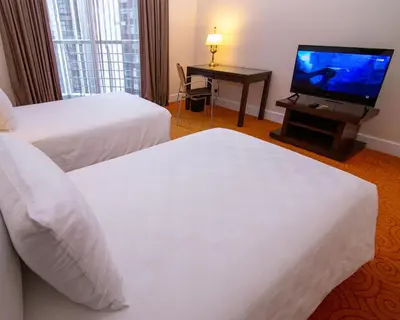 a hotel room with two beds and a flat screen tv at Perdana Kuala Lumpur City Centre in Kuala Lumpur