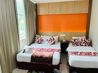 a hotel room with two beds and an orange wall at Prime Hotel at TRX Tower in Kuala Lumpur