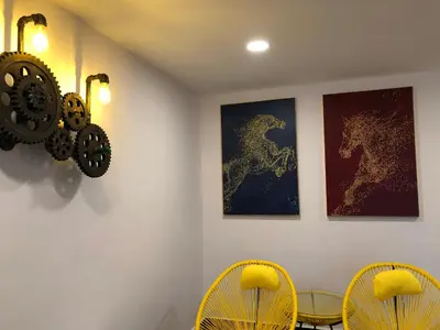 a dining room with two yellow chairs and two pictures of horses at M Design Hotel @ Taman Pertama in Kuala Lumpur