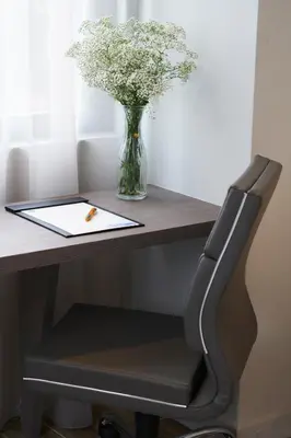 a black chair at a desk with a vase of flowers at J-Hotel by Dorsett in Kuala Lumpur
