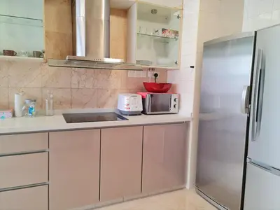 a kitchen with white cabinets and a stainless steel refrigerator at Bukit Bintang Apartment by Sarah's Lodge @ Fahrenheit88 in Kuala Lumpur