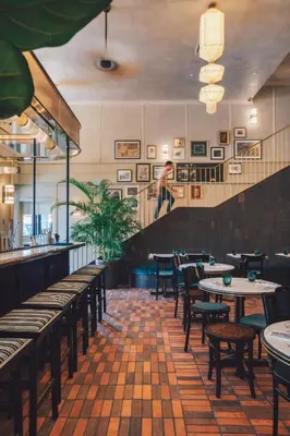 a restaurant with tables and chairs and a staircase at The Chow Kit - an Ormond Hotel in Kuala Lumpur