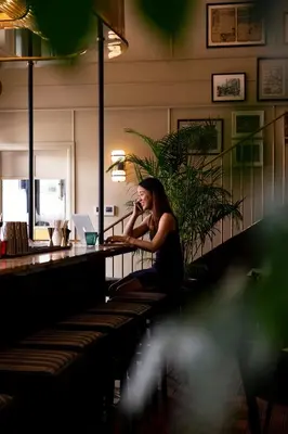 a woman sitting at a bar talking on a phone at The Chow Kit - an Ormond Hotel in Kuala Lumpur