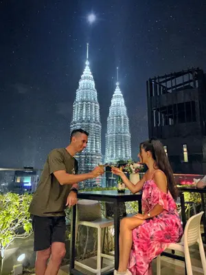 a man and a woman sitting at a table on a balcony at Like Home Star KLCC in Kuala Lumpur