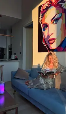 a woman sitting on a blue couch reading a book at Like Home Star KLCC in Kuala Lumpur