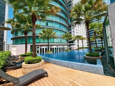 a swimming pool with palm trees and a building at Vortex Suites KLCC by BlackNest in Kuala Lumpur