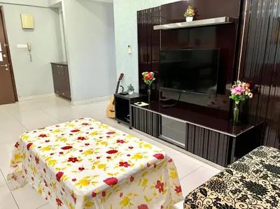 a living room with a tv and a table with flowers on it at Regalia Skypool KLCC in Kuala Lumpur