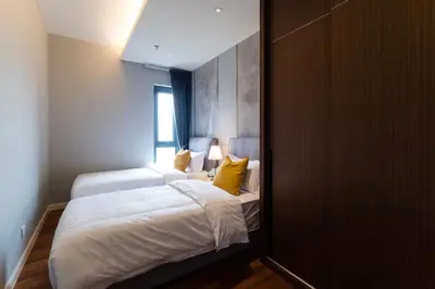 a bedroom with a bed with white sheets and yellow pillows at TriBeCa 2bedroom 3min walk to bukit bintang 2 rooftop pool in Kuala Lumpur