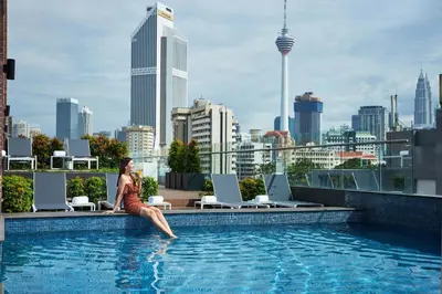 a woman sitting on the edge of a swimming pool at Four Points by Sheraton Kuala Lumpur, Chinatown in Kuala Lumpur