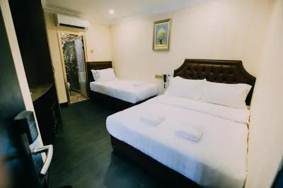 a hotel room with two beds with white sheets at Hotel Venice in Kuala Lumpur