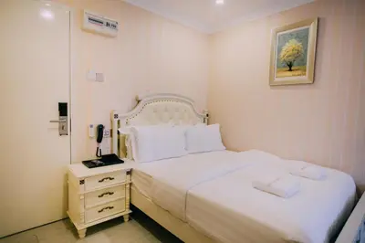 a bedroom with a white bed and a telephone at Hotel Venice in Kuala Lumpur