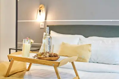 a table with a bottle and a bowl on a bed at Arte Plus KLCC Designer Suites by Cobnb in Kuala Lumpur
