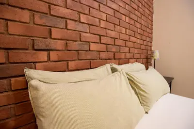 a bed with two pillows against a brick wall at Kisetsu no ie, KLCC Kuala Lumpur in Kuala Lumpur