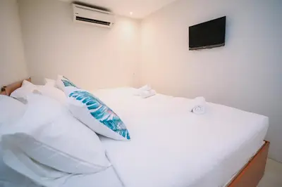 a bedroom with two beds with white pillows and a television at Swing & Pillows - KL Pekeliling in Kuala Lumpur