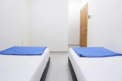 two beds in a room with a door at Hotel 3Winz Chow Kit Kuala Lumpur in Kuala Lumpur