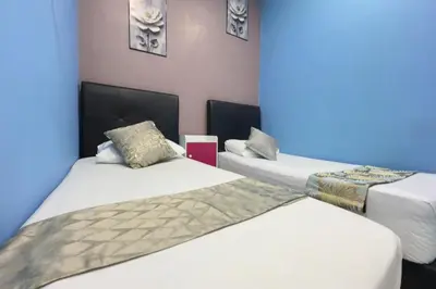 a room with two beds and a blue wall at Hotel 3Winz Chow Kit Kuala Lumpur in Kuala Lumpur