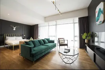 a living room with a green couch and a bed at Anggun Residence KLCC By Sleepy Bear in Kuala Lumpur