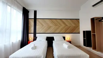 two beds in a room with white walls and windows at Arte Plus By Sleepy Bear in Batu Empat