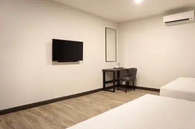 a white room with a desk and a television on a wall at ACES Hotel Kuala Lumpur in Kuala Lumpur
