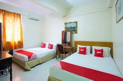 a bedroom with two beds and a desk and a table at Hotel O Perfect Class Hotel in Kuala Lumpur