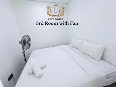 a bedroom with a white bed and a room with a fan at Luxe Suites at Vortex KLCC in Kuala Lumpur