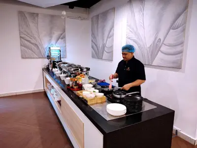 a man standing in a kitchen preparing food at Cormar Suites Kuala Lumpur in Kuala Lumpur